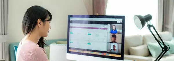 A lady having a meeting with her workmates in front of a computer monitor